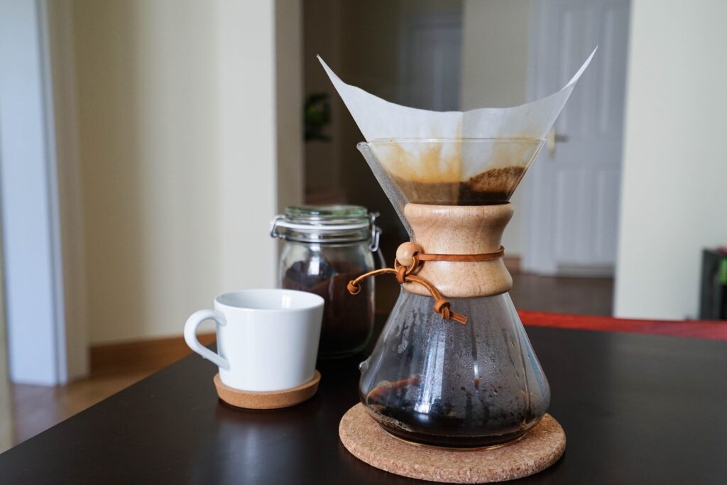 A pour-over Chemex coffee brewer alongside a fresh brewed cup of specialty coffee.