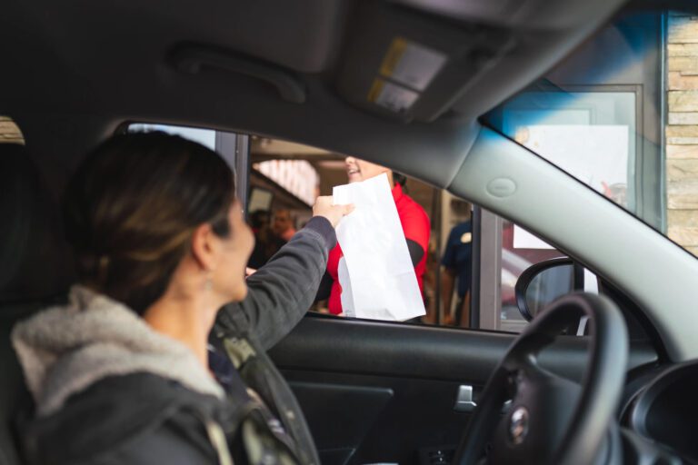 Woman ordering unhealthy fast food from the drive-through window.