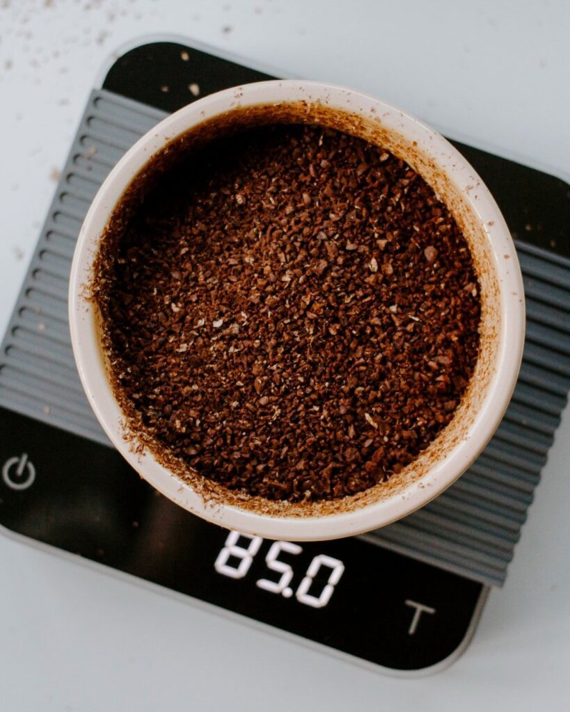 Dry, coarse specialty coffee grounds being weighed in preparation to become delicious cold brew coffee.