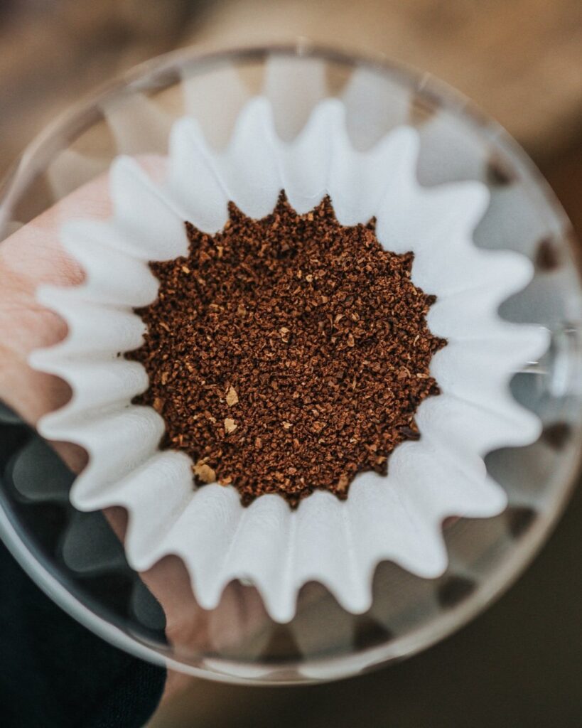 Dry specialty coffee grounds resting in a filter waiting to be brewed.