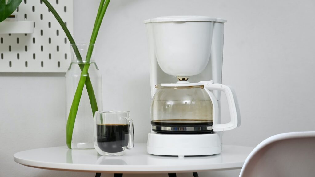 Coffee machine and coffee cup in office room.