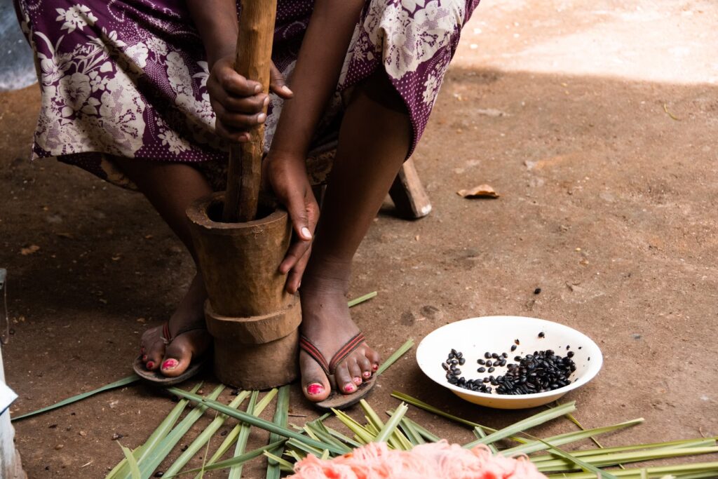 An Ethiopian woman grinding coffee beans with a mortar and pestle for the traditional coffee ceremony. - "The Black History of Coffee"